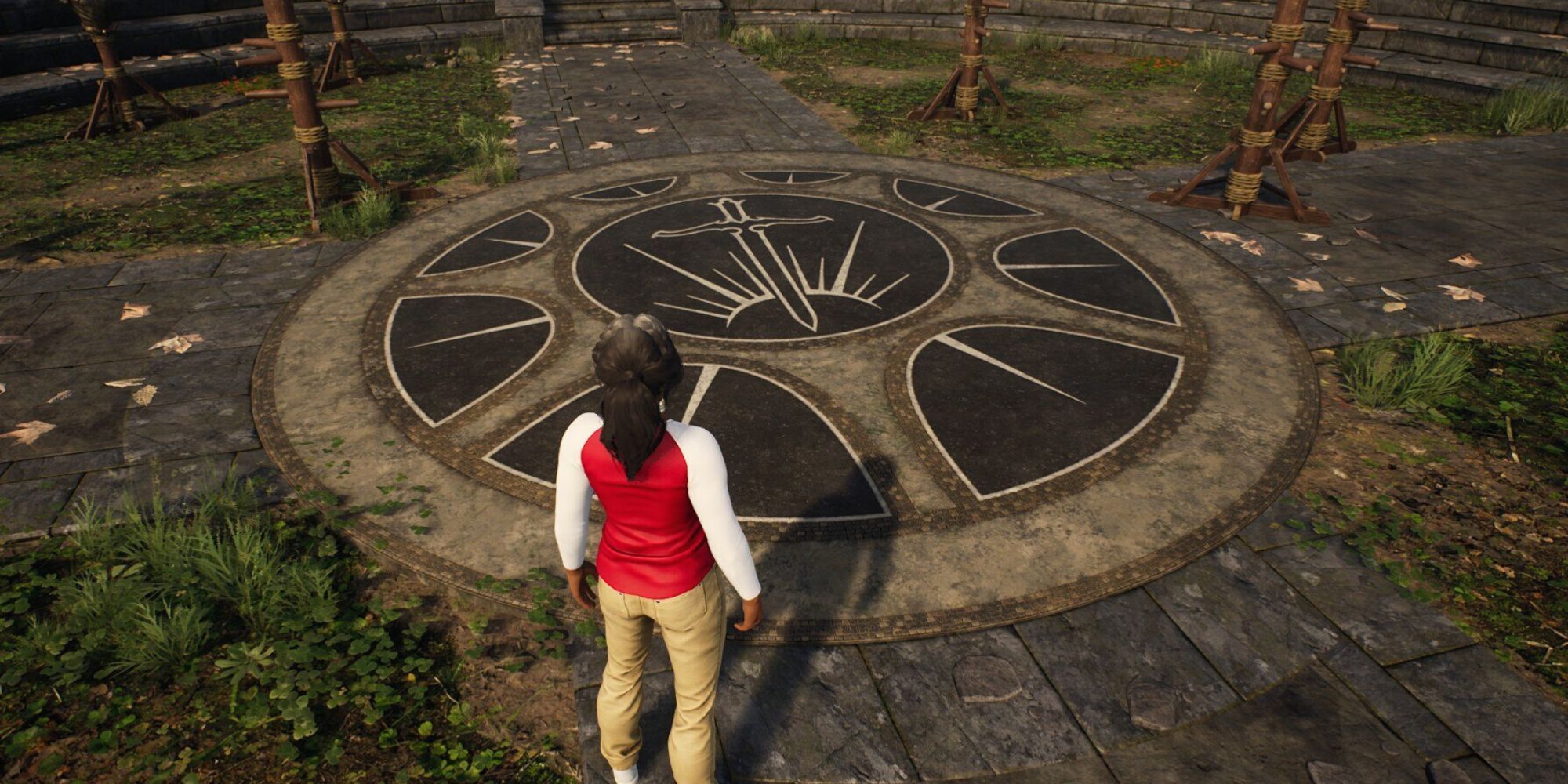Hunter standing next to a shield painting on the floor of The Yard. There is a sword at the centre of the shield.
