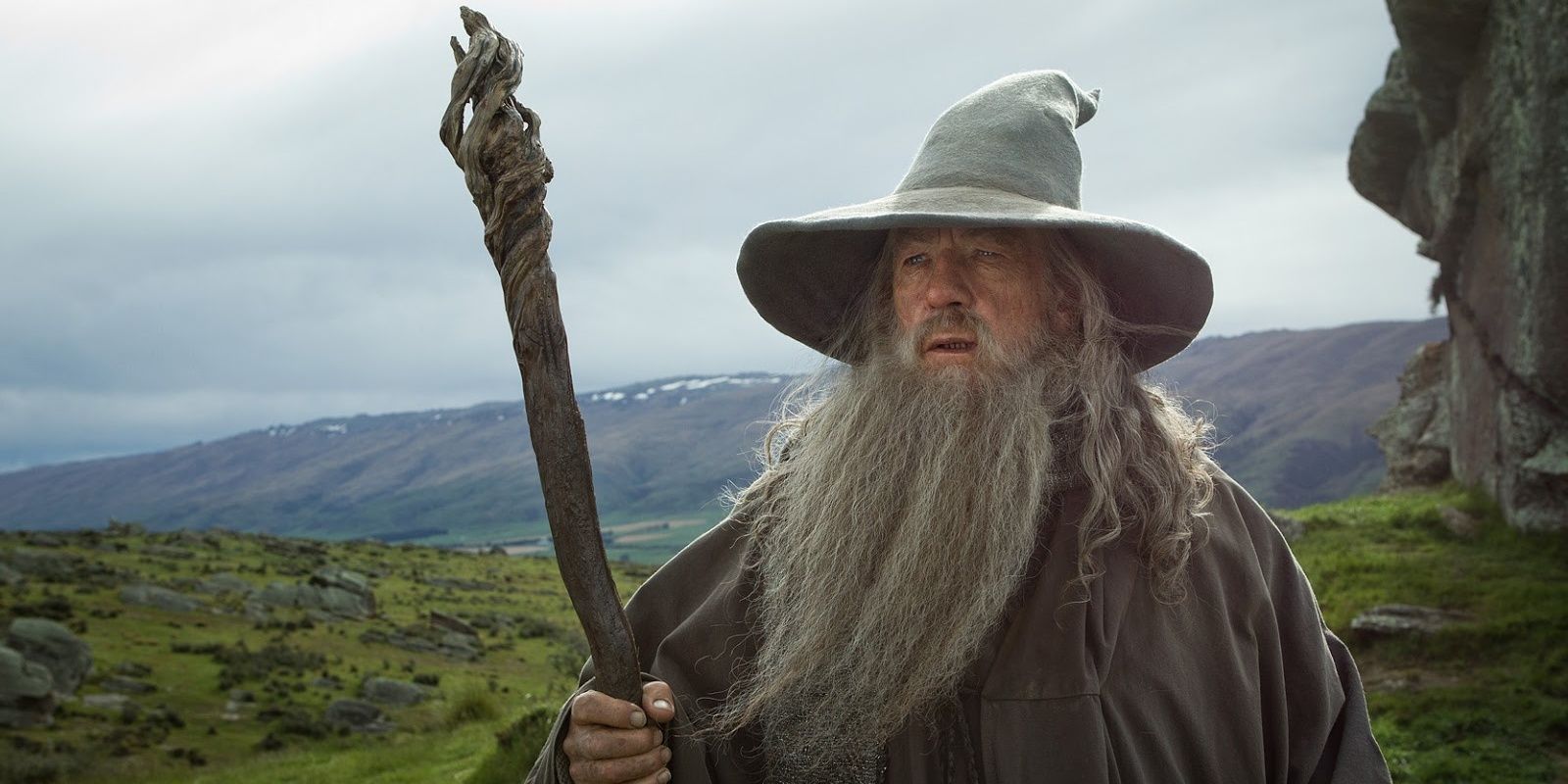 gandalf the grey standing in scenic hills with staff hat and robes