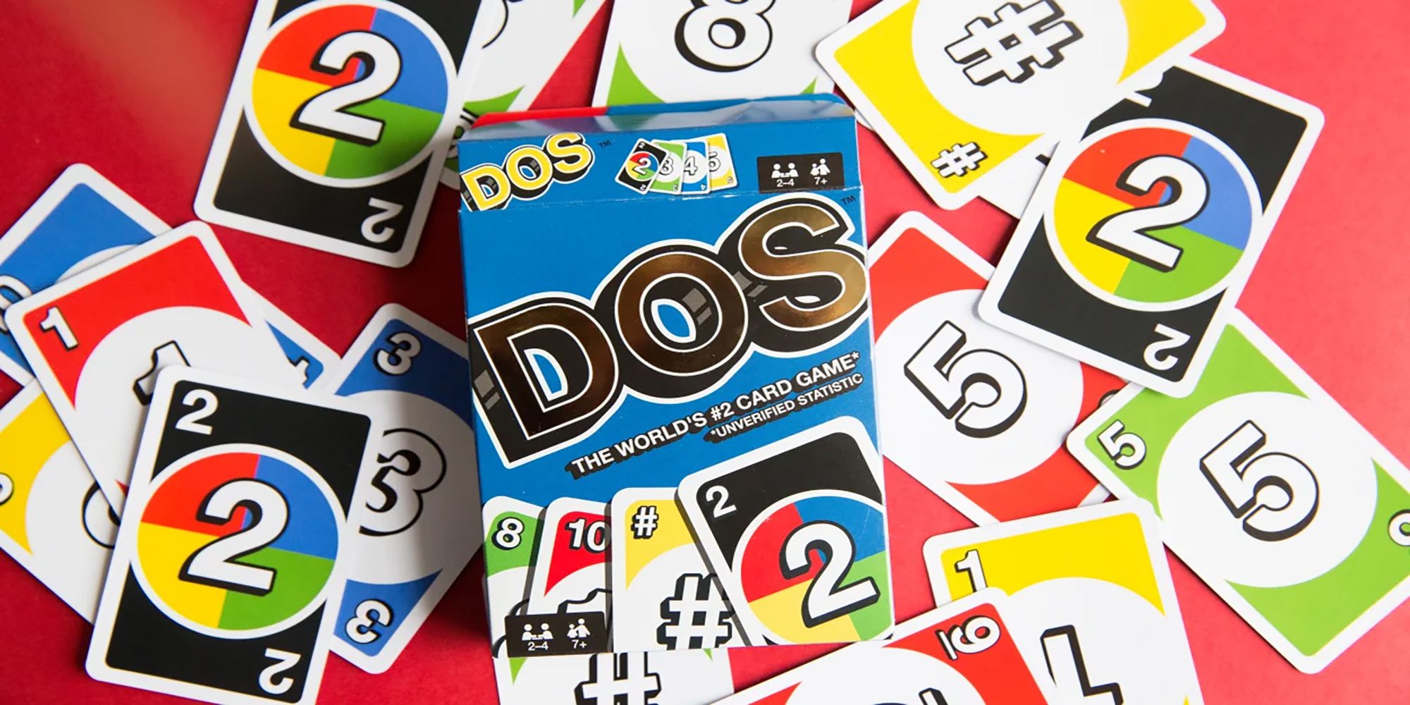 A DOS card game set sits on a red table with several colorful cards with numbers and symbols on them.