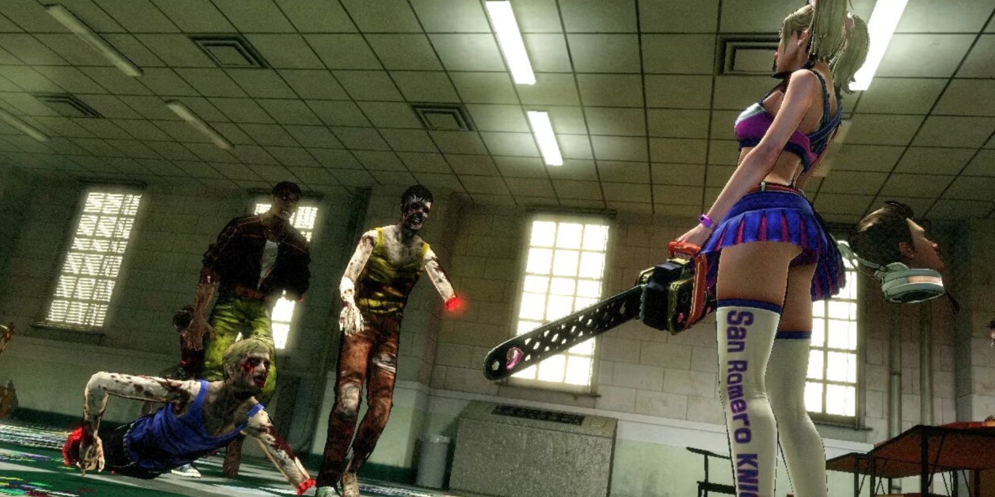 Juliet Starling wielding a chainsaw and facing three zombies in a school classroom in Lollipop Chainsaw