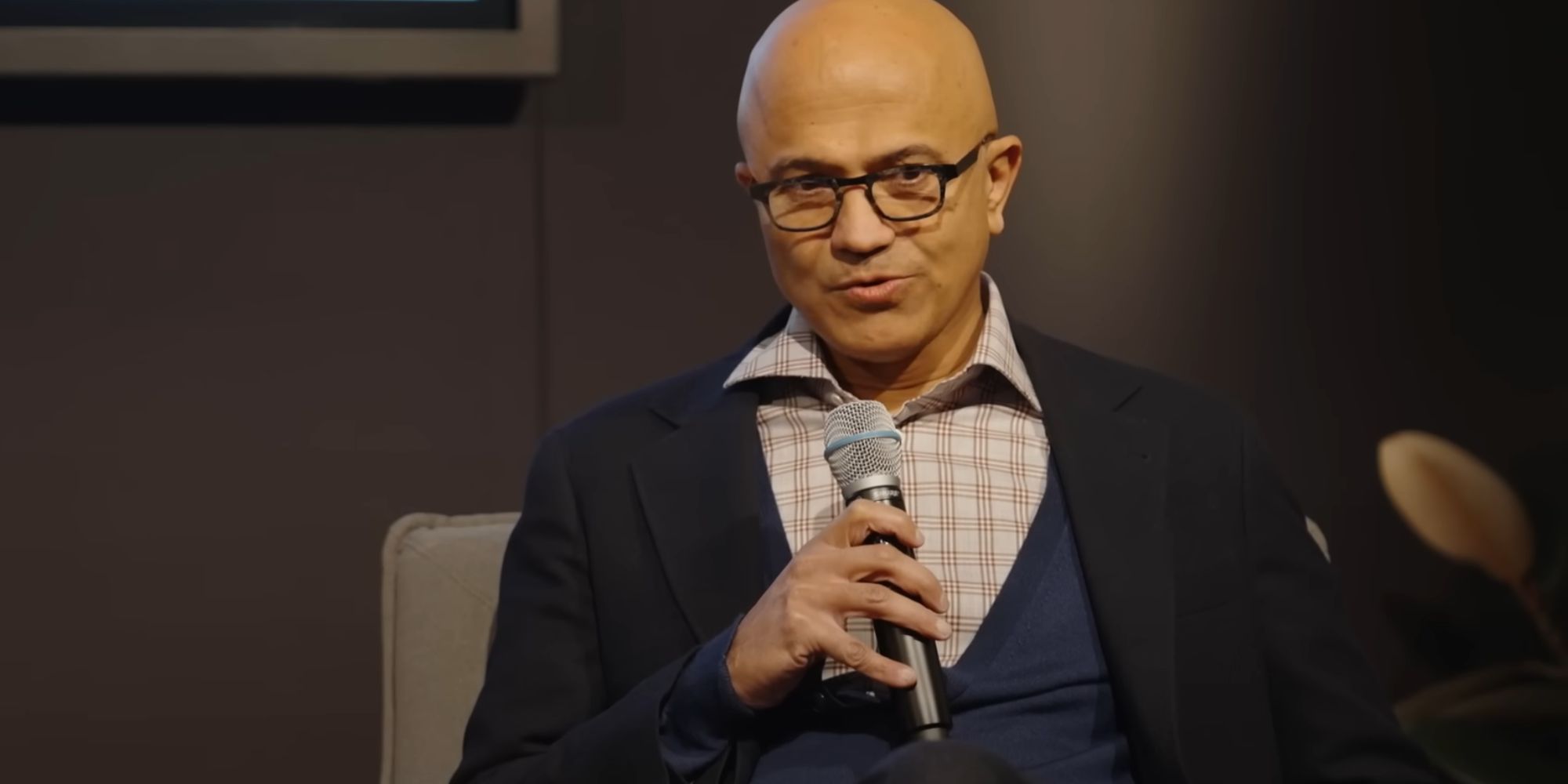 Microsoft CEO Satya Nadella being interviewed, holding a microphone