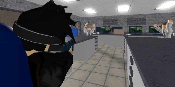 Two scientists in a lab with their hands above their head as a robber points a gun in their direction