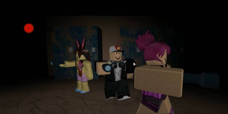 Three players with flashlights out in a dark hallway