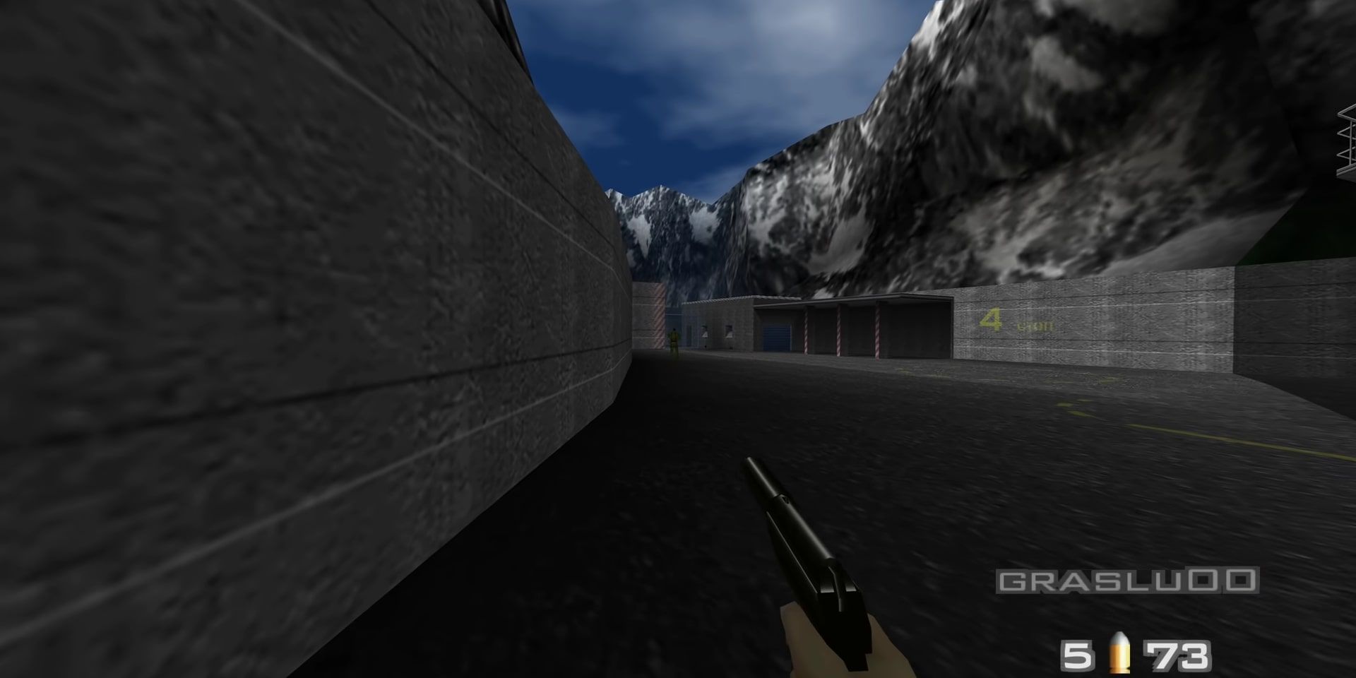 007 running around the exterior of the Dam facility near some snowcapped mountains, sights set on a guard.