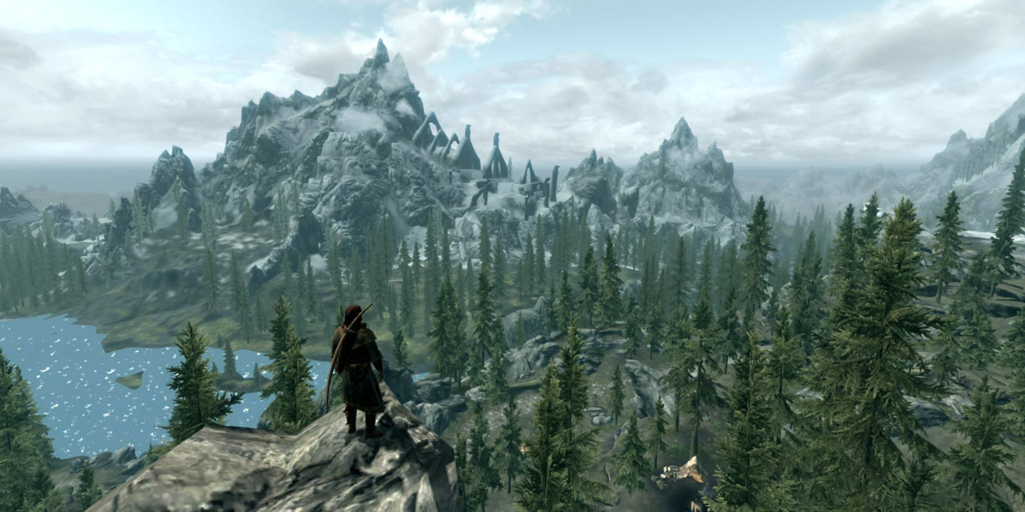 Dragonborn on top of cliff looking out at snowy mountains and Bleak Falls Barrow in the distance in Skyrim