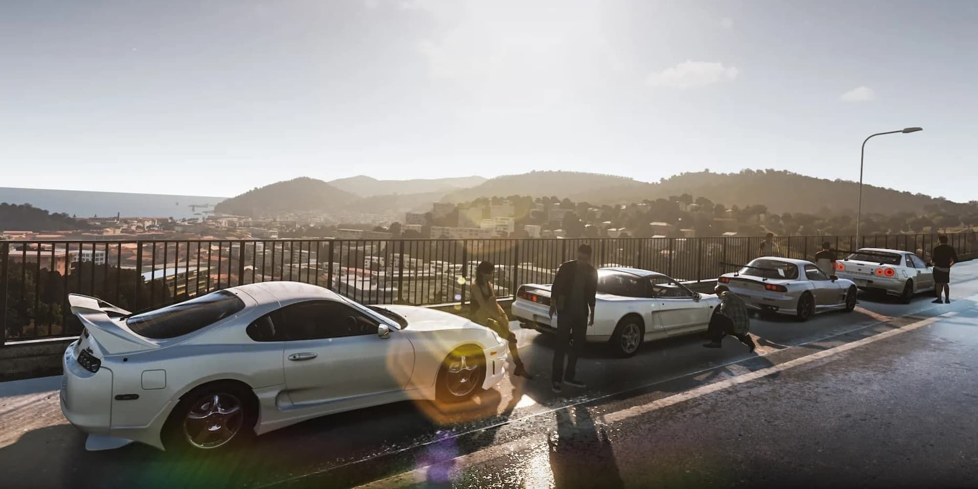Four white cars line up near a fence on the road with their owners hanging out around them in Forza Horizon 2.
