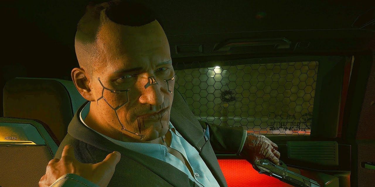 Jackie hurt in back seat of a car talking to V in Cyberpunk 2077.