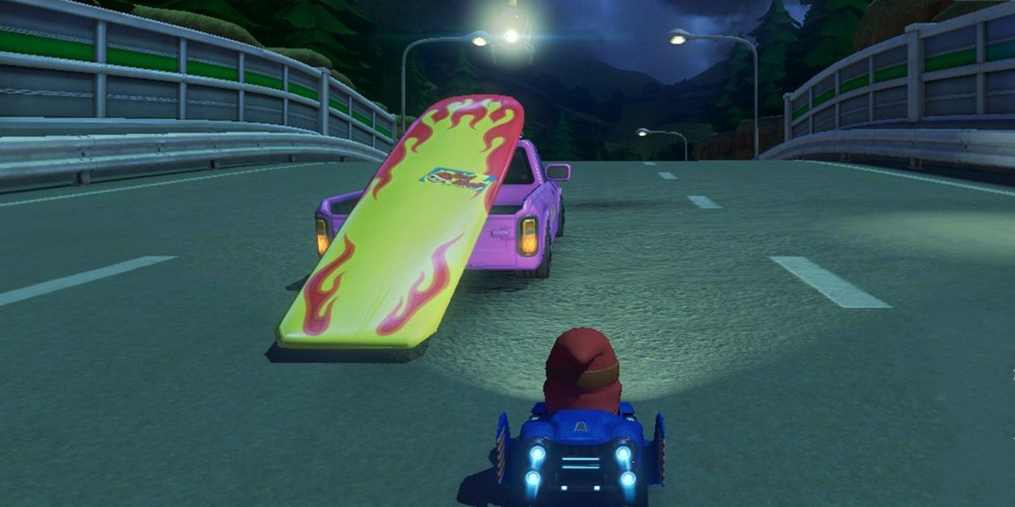 A pink truck carrying an oversized surfboard drives in front of Mario - Mario Kart 8
