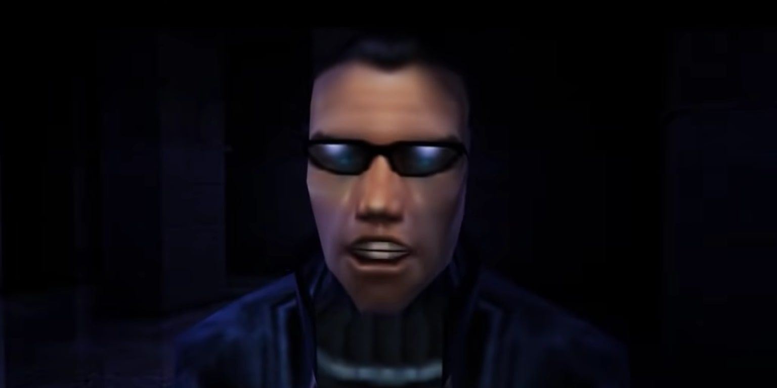 JC Denton with his mouth open in conversation, wearing shades, in a dark room in Deus Ex.
