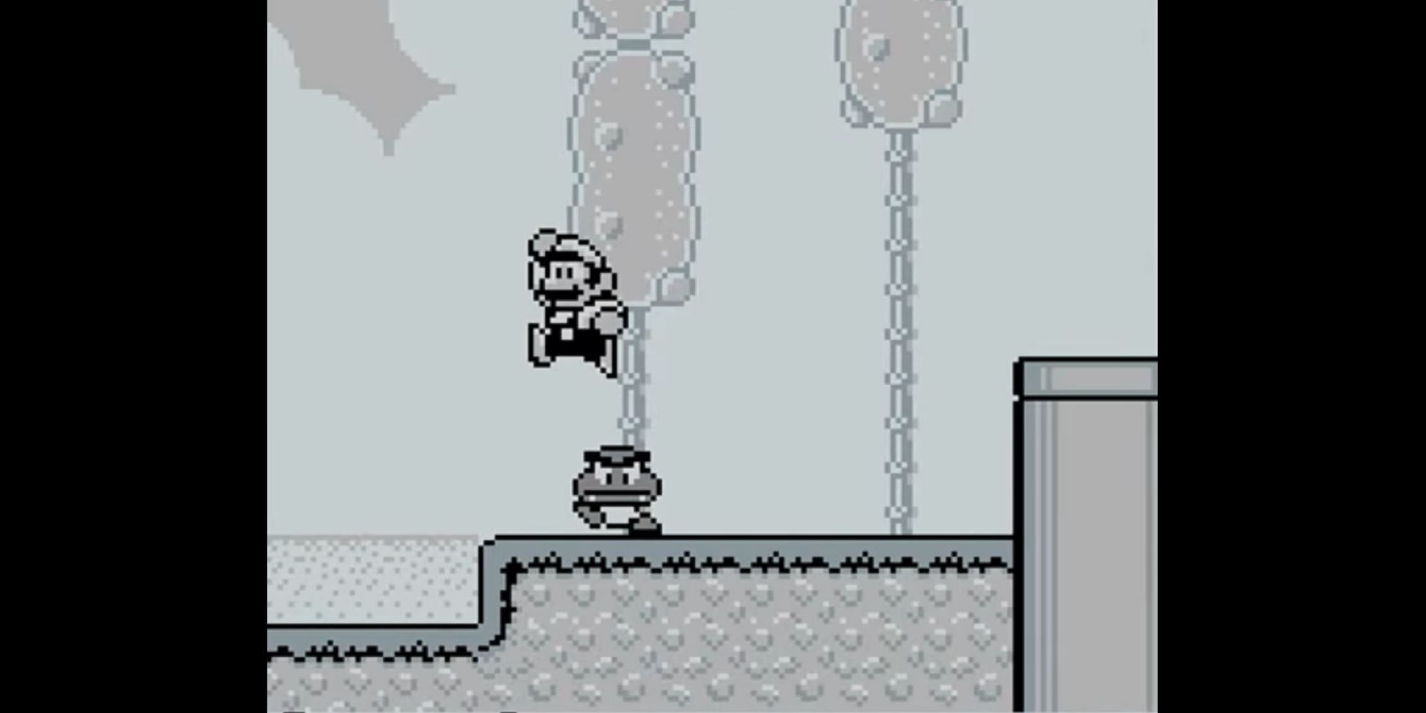 Mario jumps on a Goomba near a pipe in Super Mario Land 2