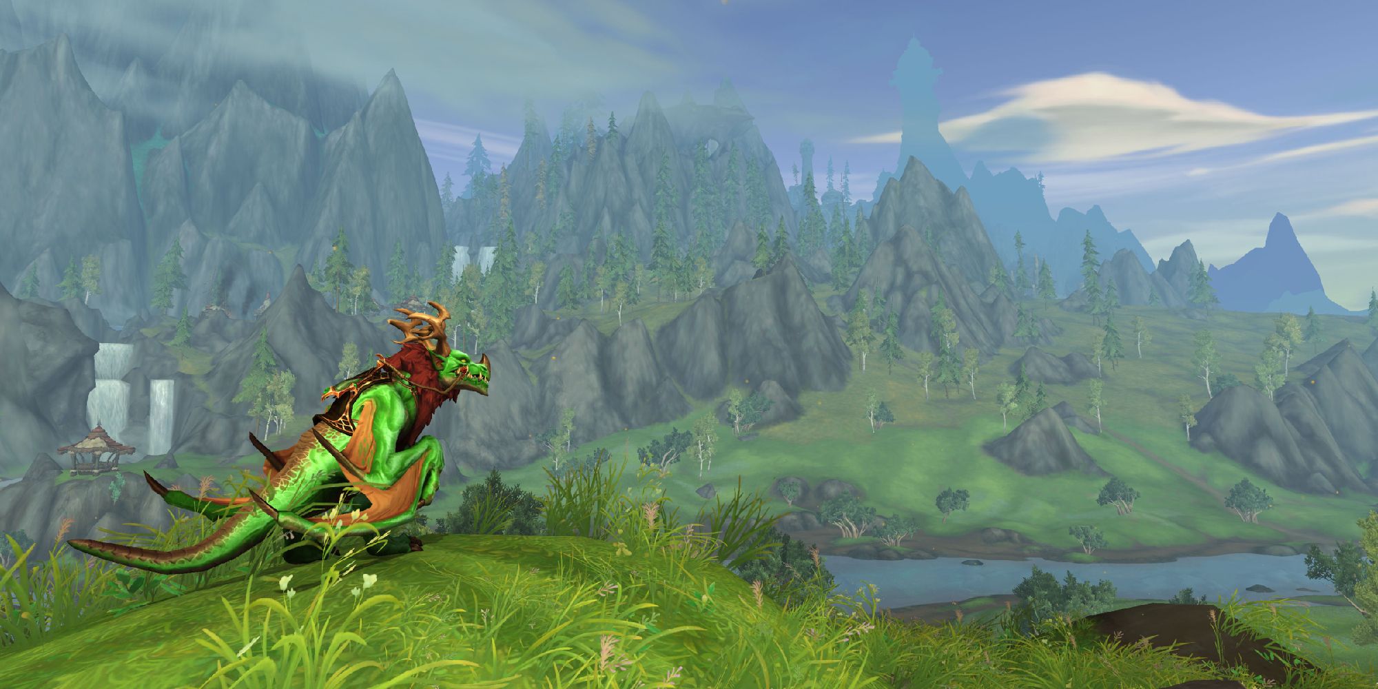 dragon perched on edge of grassy hill looking towards mountainy area