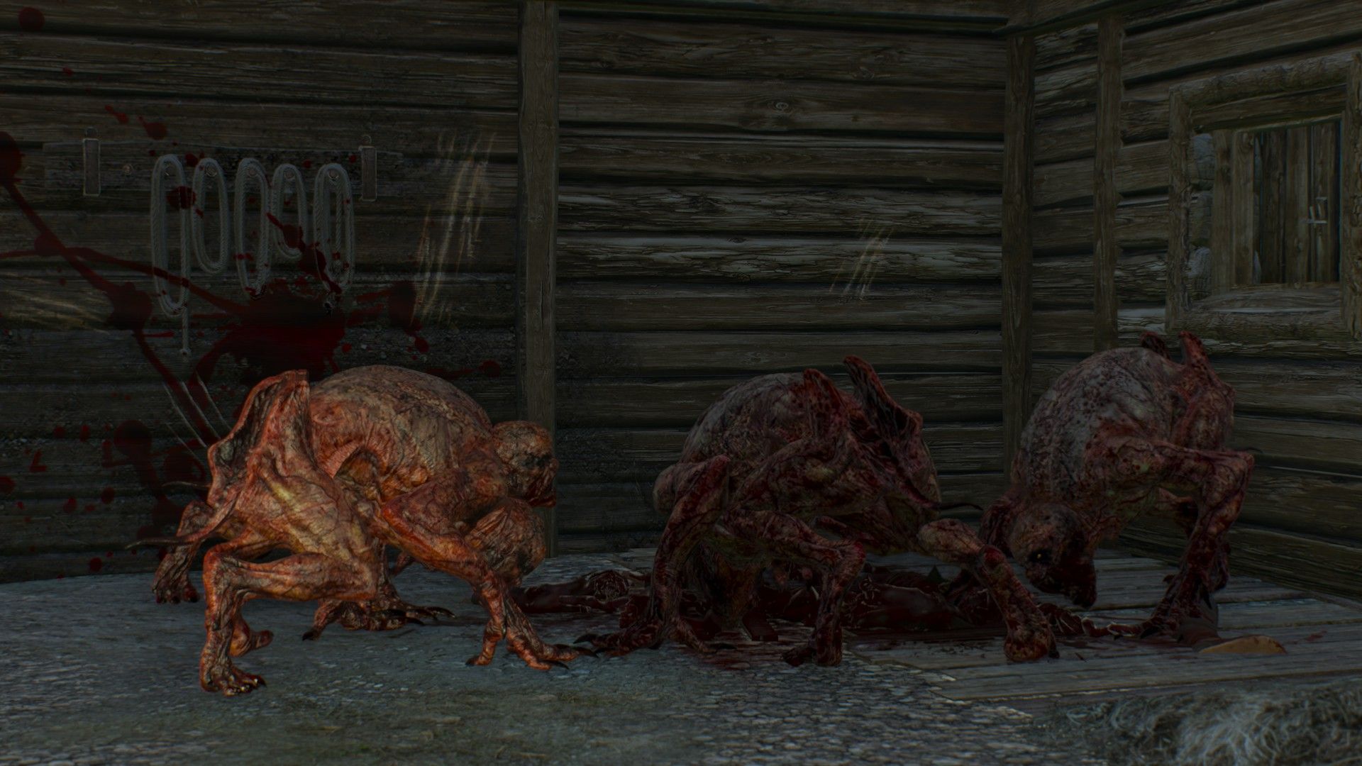 A quartet of ghouls crouch around a pile of human remains, devouring the meat in a dark barn.