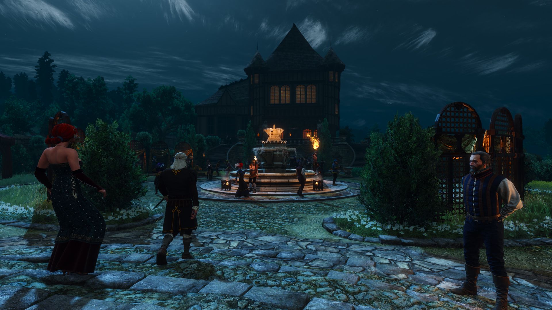 A wide angle screenshot of Geralt and Triss walking into a lavish estate at night.