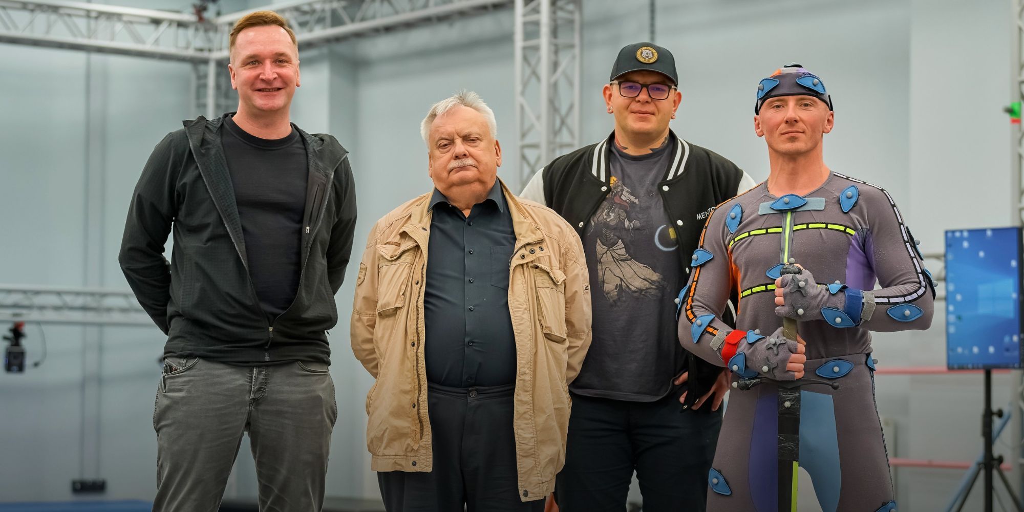 The Witcher author Andrzej Sapkowski visits CD Projekt Red. He poses with an actor in mocap, holding a prop sword.