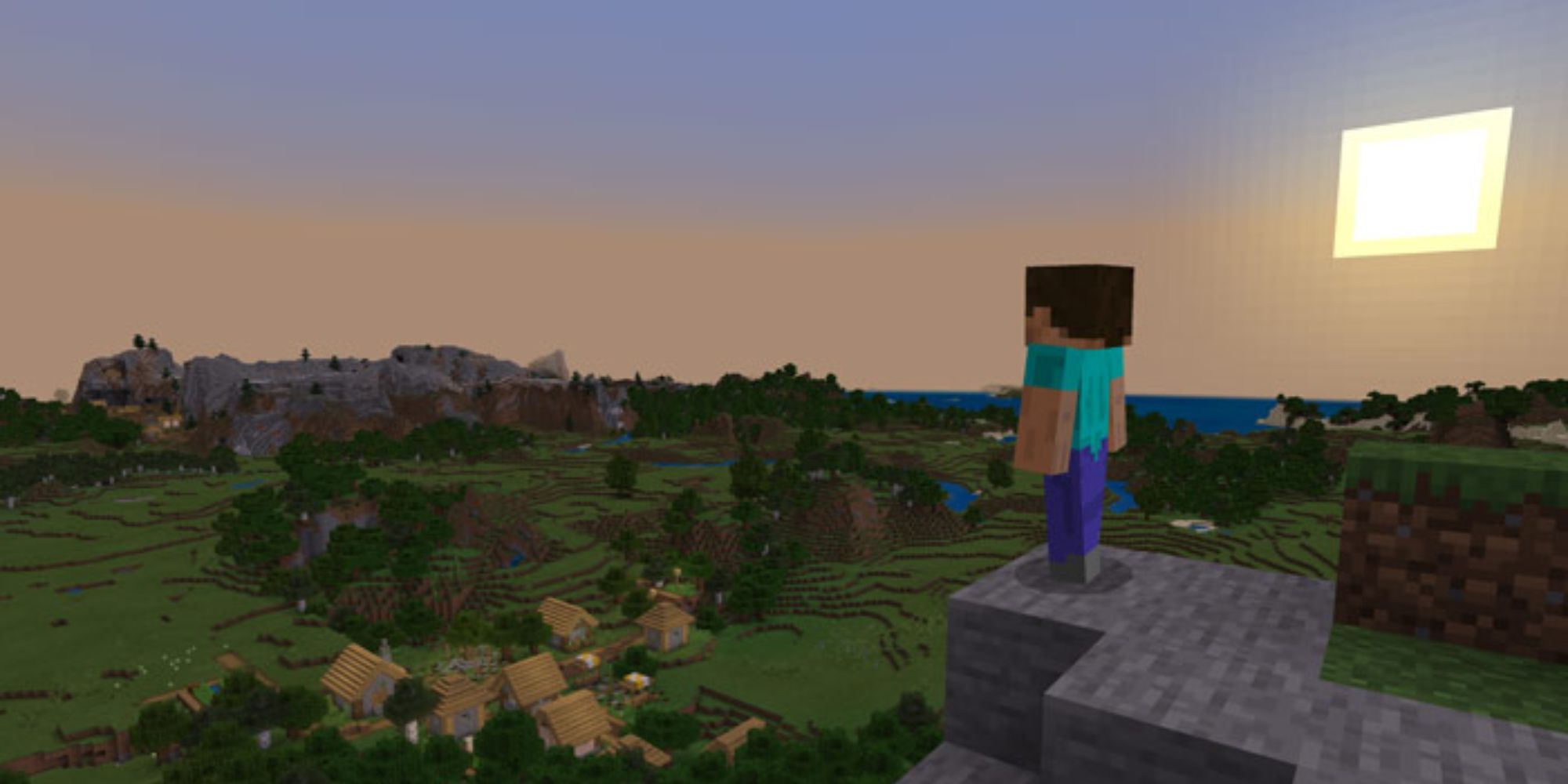 Steve stands on a rocky ledge overlooking a village 