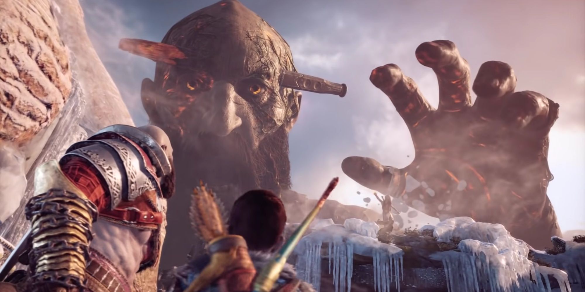 The formerly dead giant Thamur being brought back to life by Freya's magic, reaching a giant hand out toward Kratos and Atreus as they look up at it.
