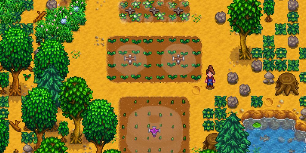 Stardew Valley Farmer standing next to patches of tilled land with sprinklers going
