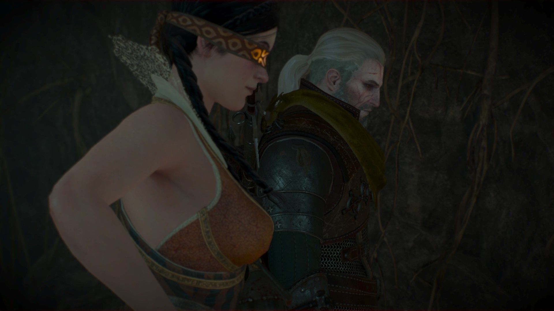 Geralt and Philippa stand inside a cave, staring at something outside of shot.