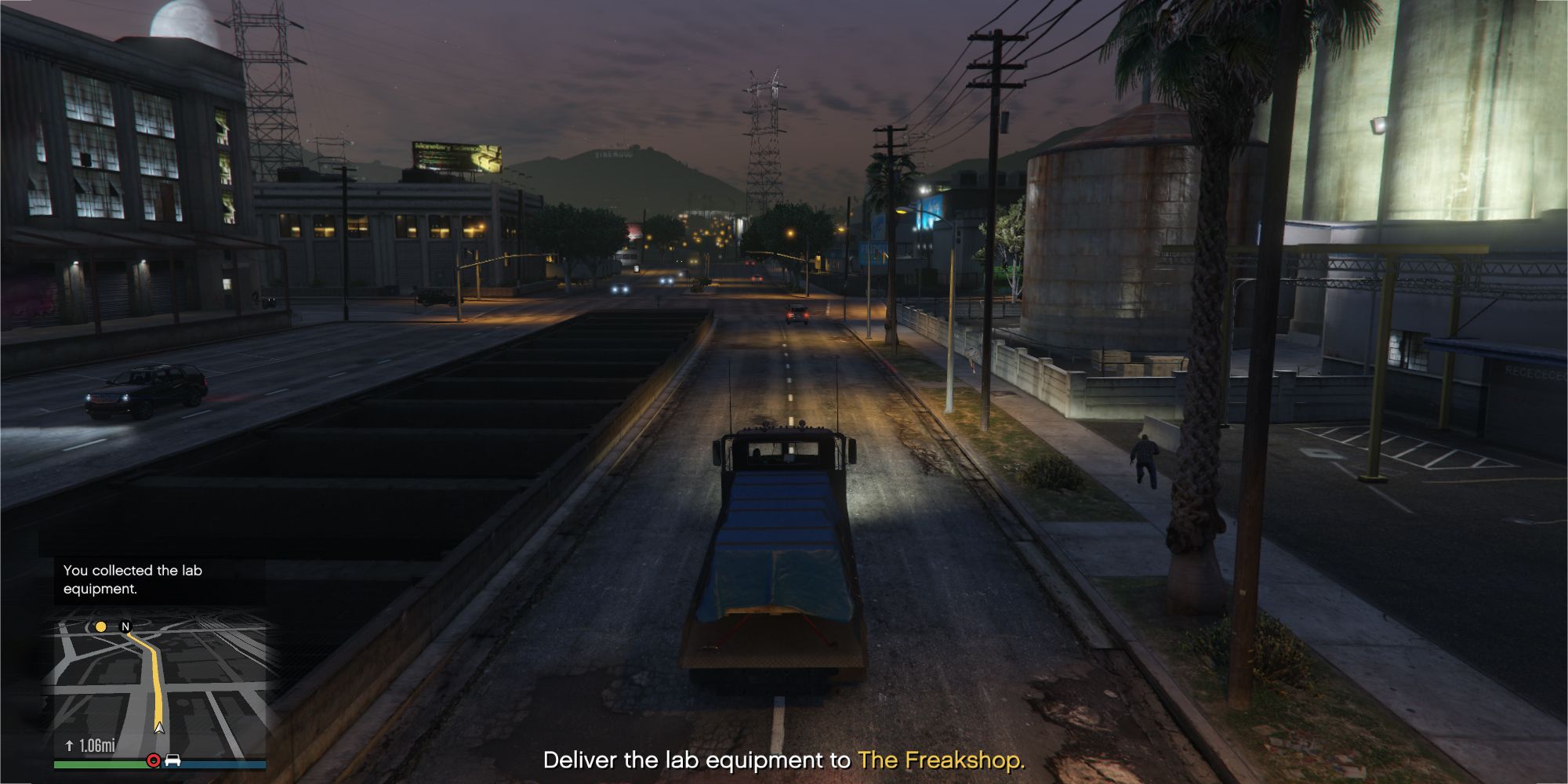 The image shows a Grand Theft Auto Online player in a truck with a bed covered in a blue sheet on the main road.  The text in the bottom center reads 