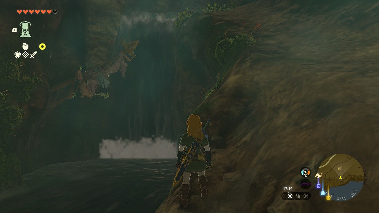 The Legend of Zelda: Tears of the Kingdom - In a cave on the North Hyrule Plain, Link stares at a waterfall with climbing gear behind it.