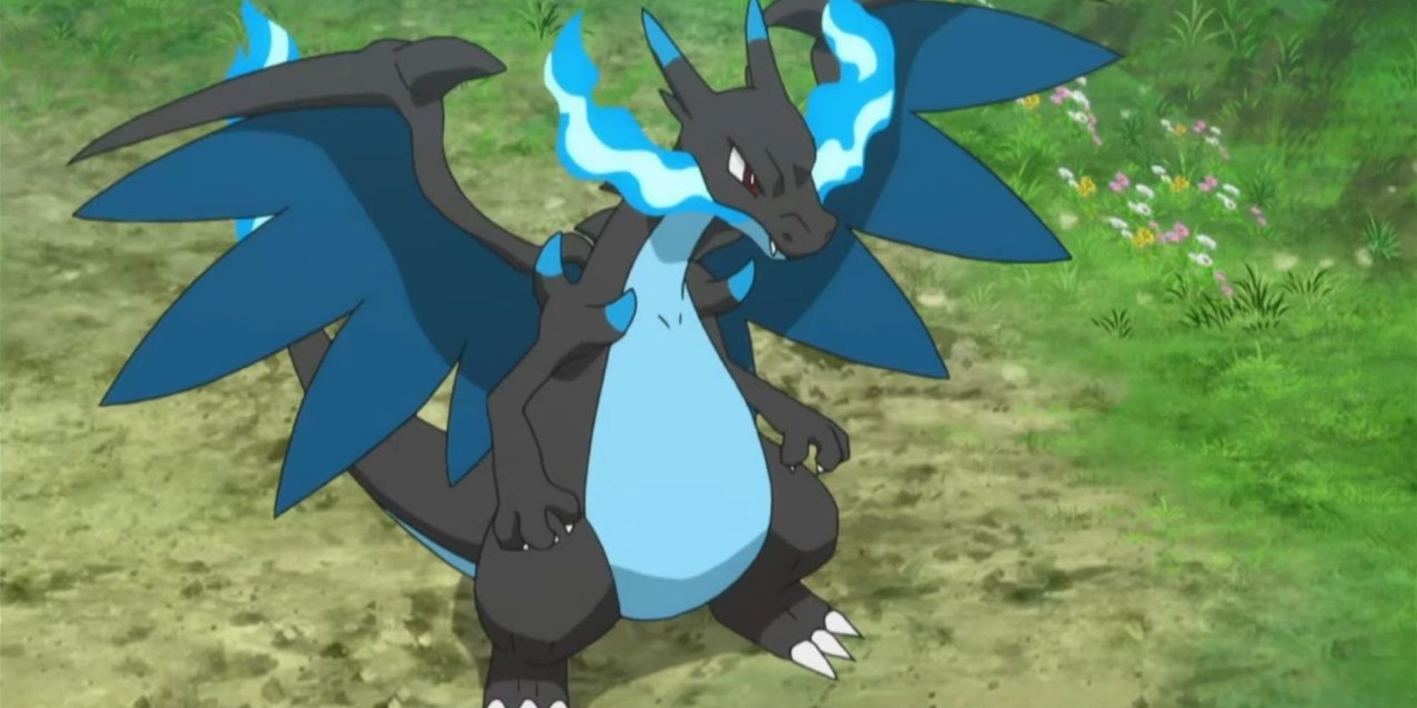 Mega Charizard X stands on a dirt path by some grass in the Pokemon anime.