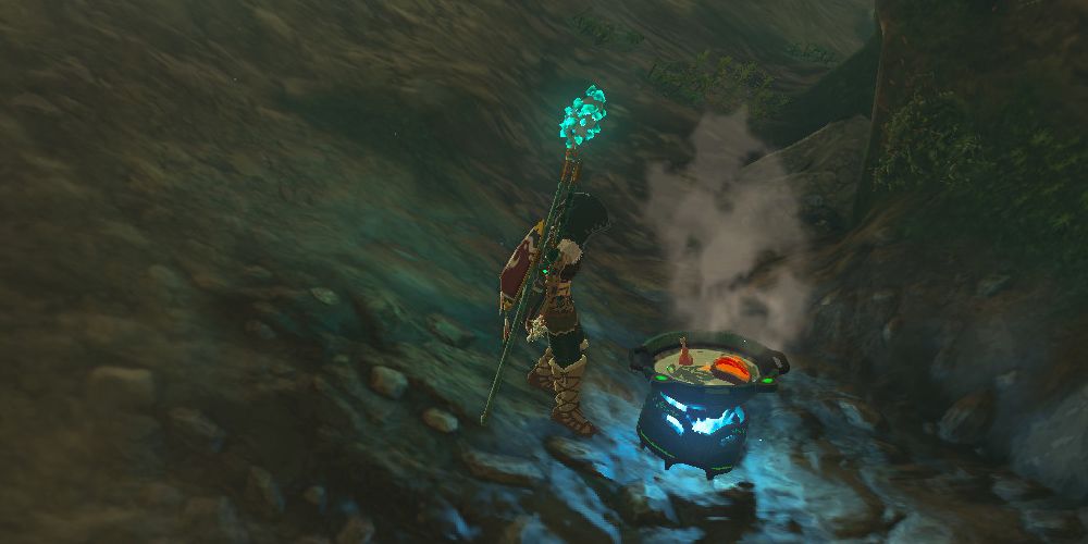 Tears of the Kingdom Link standing in a cave, cooking in a portable pot