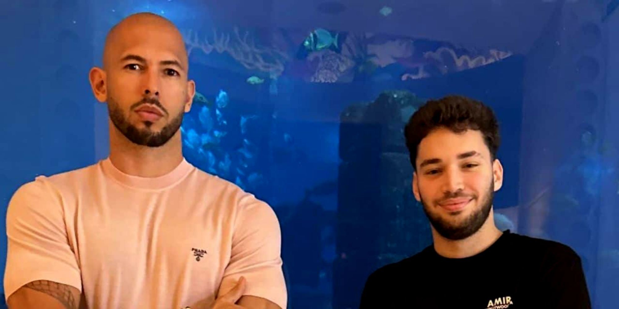 Andrew Tate standing next to Adin Ross. There is an aquarium behind them. 