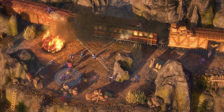 Party members of Desperados 3 engaging in a gunfight with soldiers from the top of a train with a fire nearby.