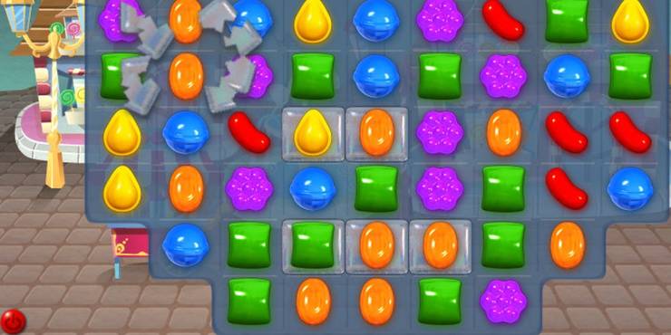 A board in Candy Crush with some encased candies at the bottom and one candy breaking free of encasement