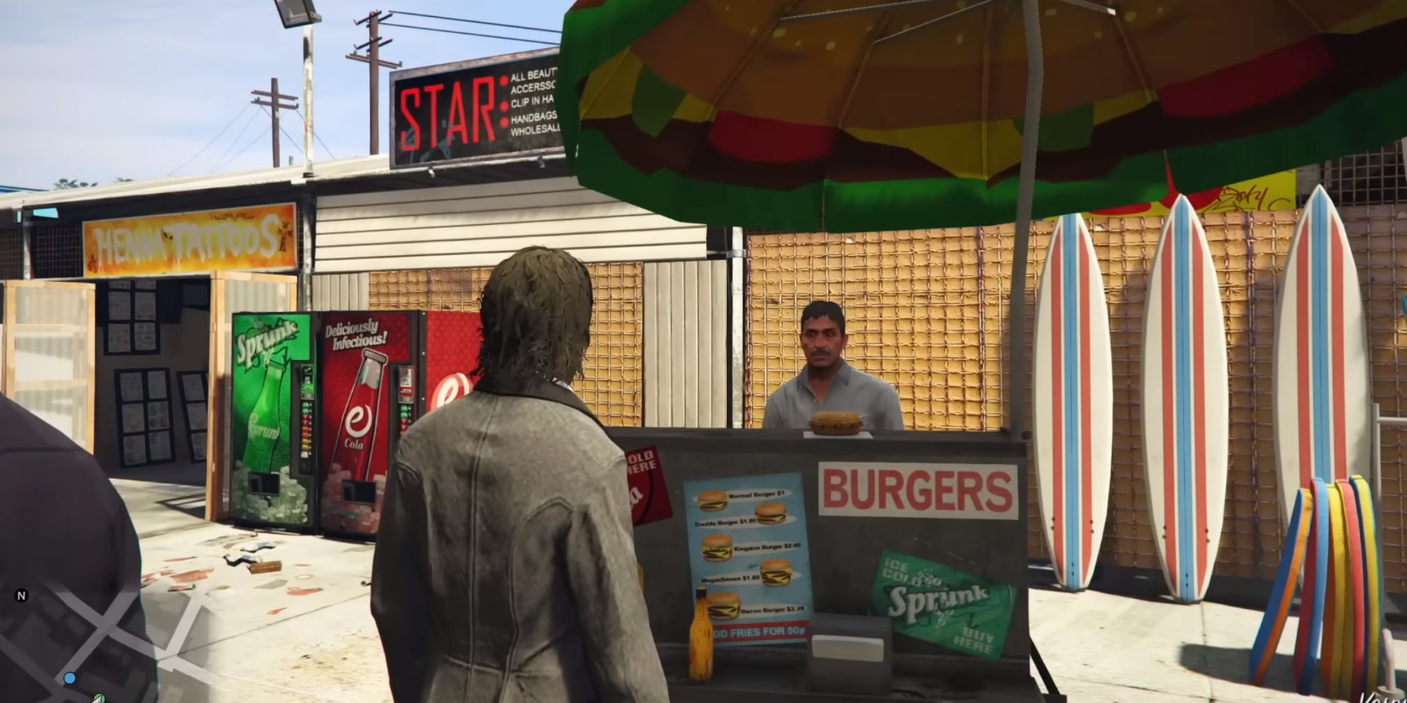 A man stands at a burger stand on a sunny street. It appears to be near a beach. The screenshot is from GTA 5.