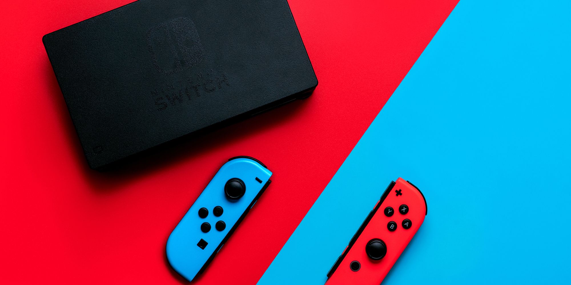 Nintendo Switch dock on the left, over a red slanted background, with the blue joy-con, while the red joy-con is on the right side over a blue-slanted background