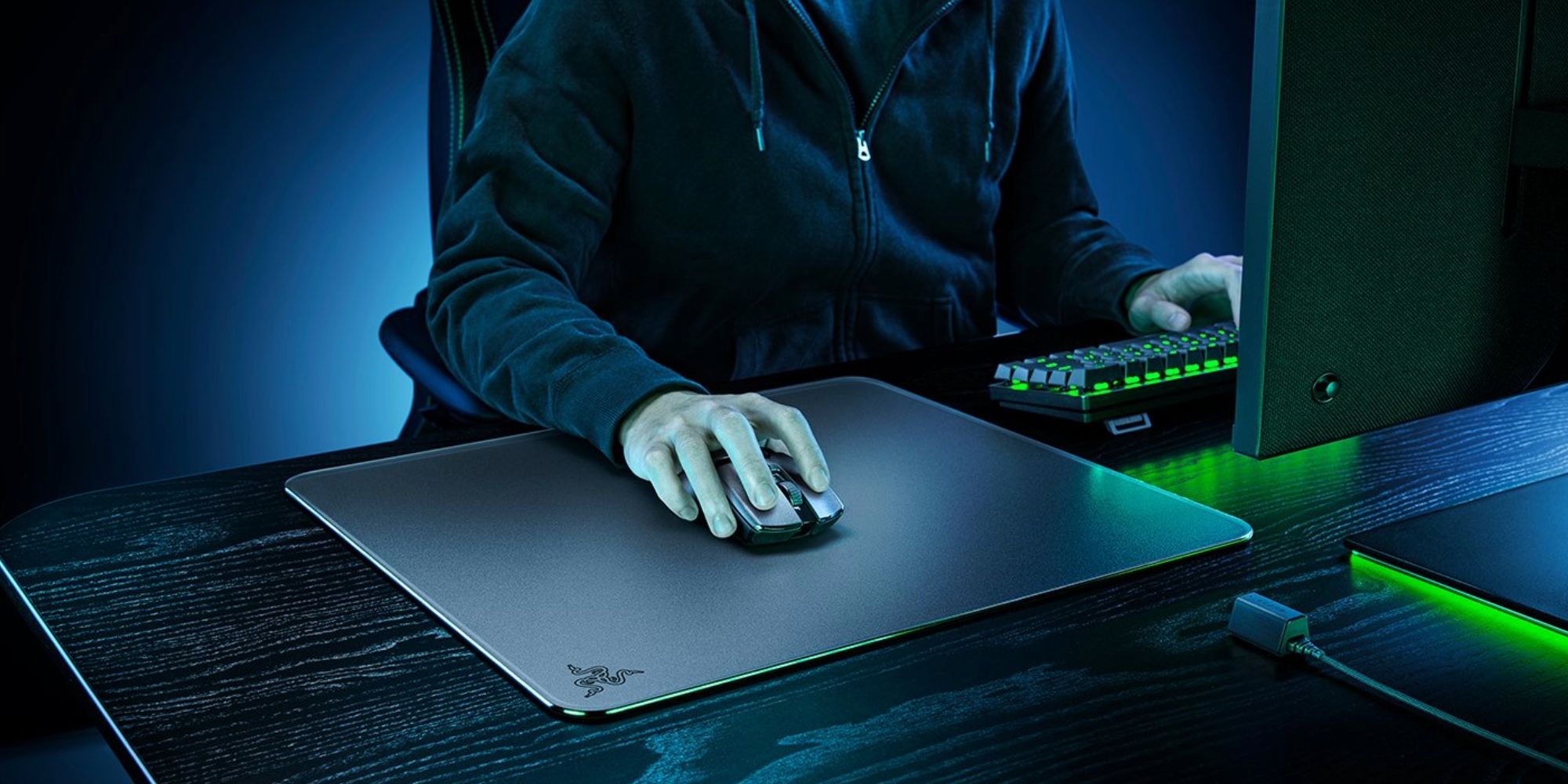A person using a wireless mouse rests their hand on a black glass mouse pad.