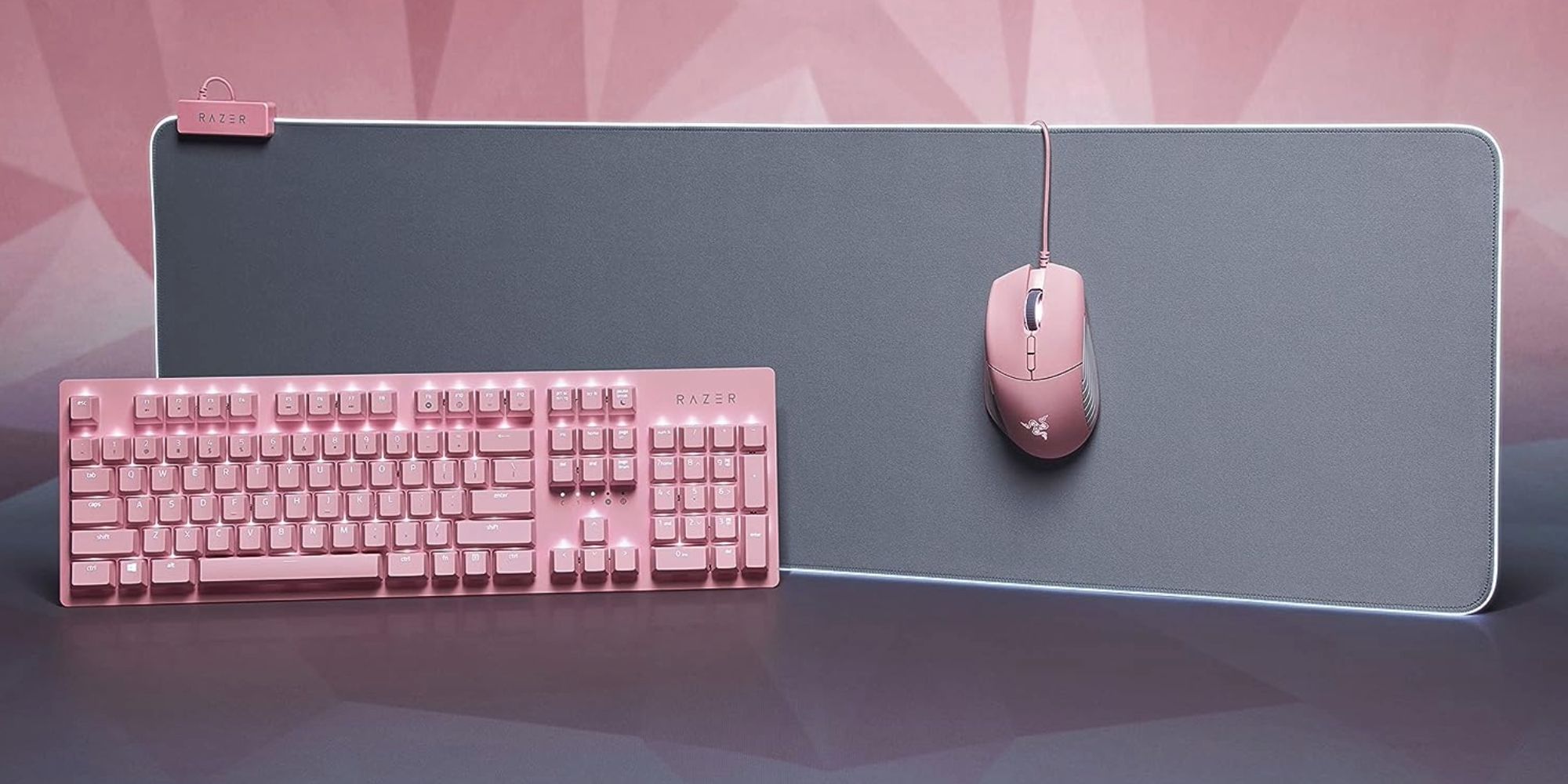 A large grey mouse pad with pink accents is displayed with a matching pink keyboard and mouse. 