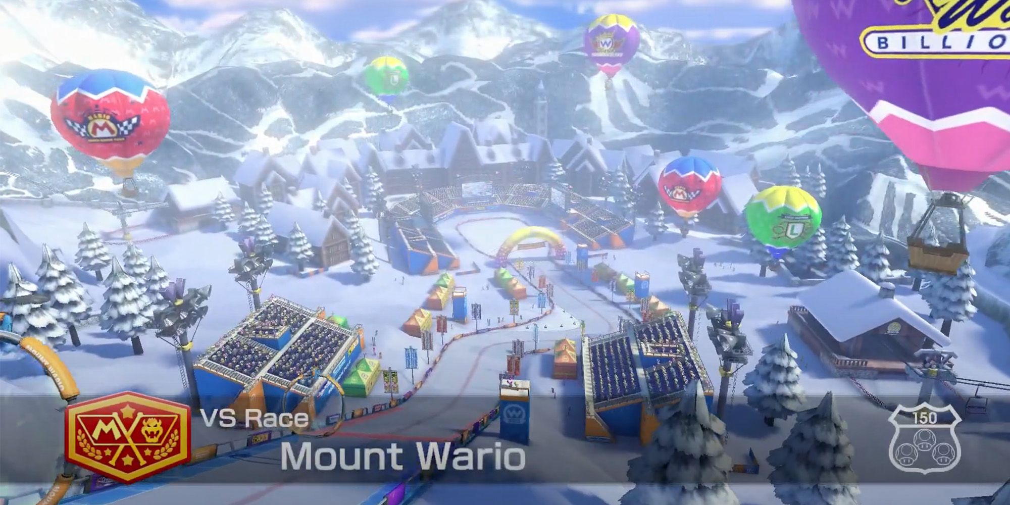 Mario Kart 8 Deluxe - Mount Wario - A Snowy Mountain With Houses, Trees, And Crowds Of People. Several Colorful Hot Air Balloons Are In The Air