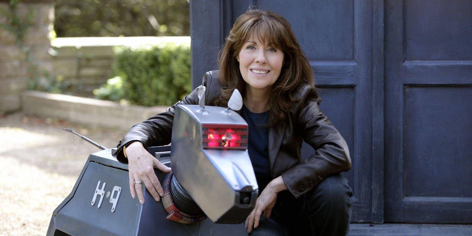 A woman crouching down next to a robot dog outside the TARDIS