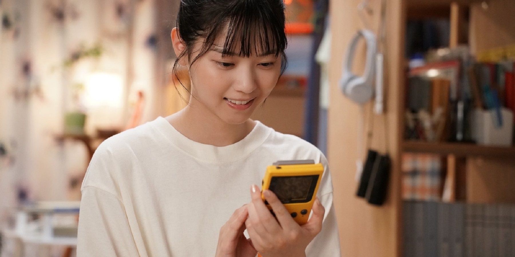 a woman from the live action pokemon tv show poketsume looks at her game boy