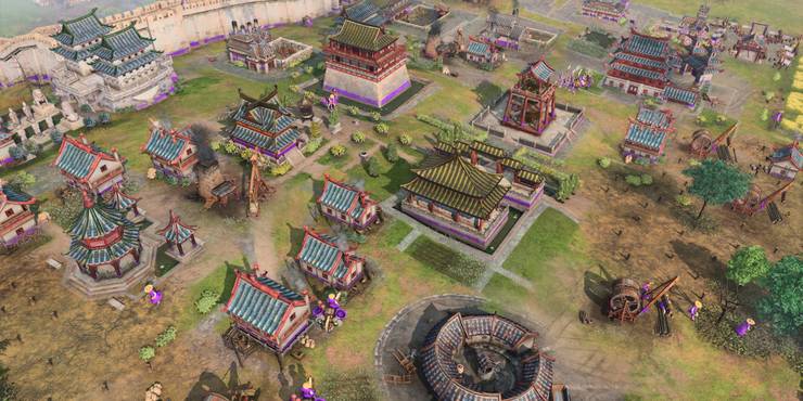 A bustling settlement has workers dressed in purple in Age of Empires 4.