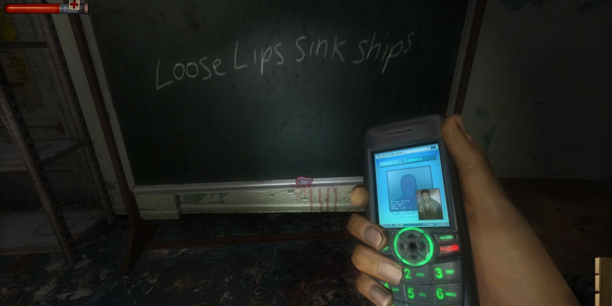 A first-person perspective of a phone with green buttons and a blue screen, with a chalkboard in the background in Condemned: Criminal Origins.