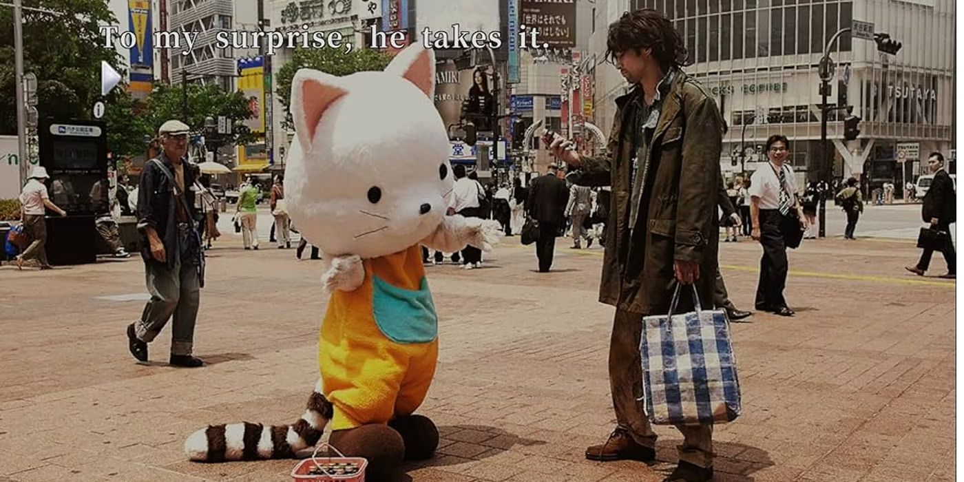 A kitten mascot interacts with a stranger on the sidewalk.
