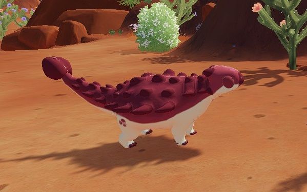 Maroon and white Pinacosaurus with its eyes closed standing in Ariacotta Canyon near some cacti during the day in Paleo Pines.
