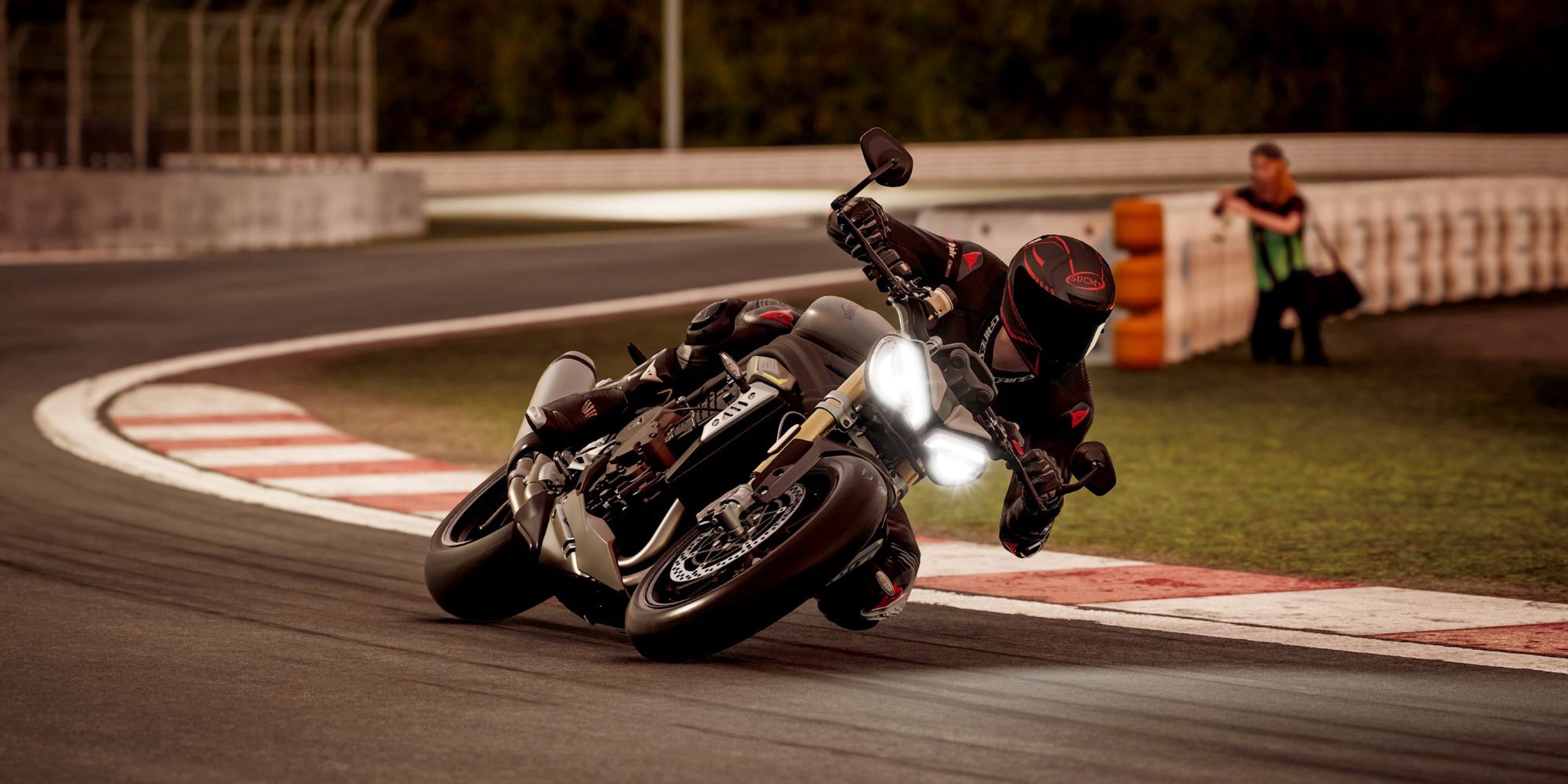 A black sports bike with bright headlights rounds a bend at high speed.