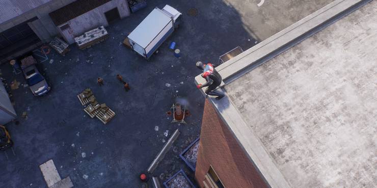 Spider-Man sits on the corner of a rooftop, watching enemies below in Spider-Man 2.