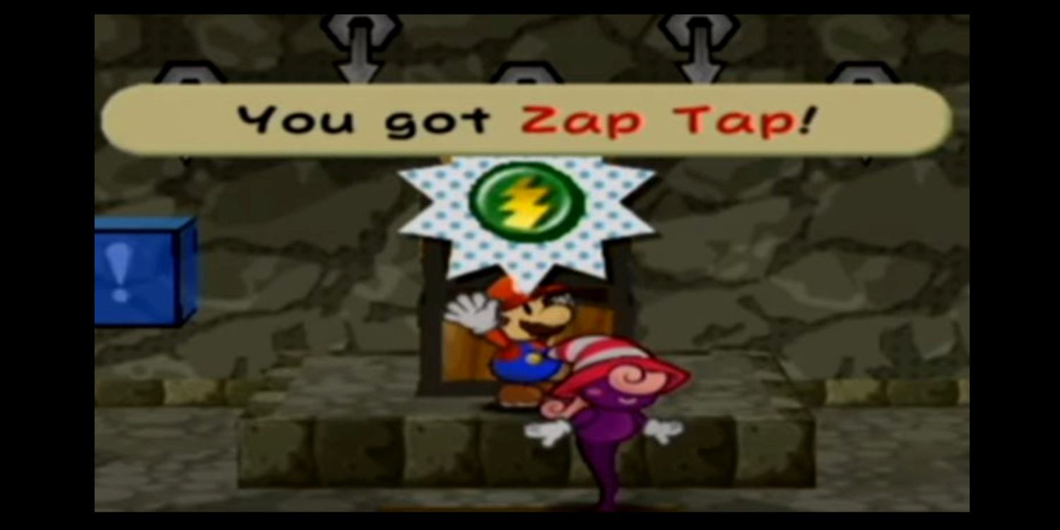 Mario stands in front of a giant chest holding the Zap Tap badge