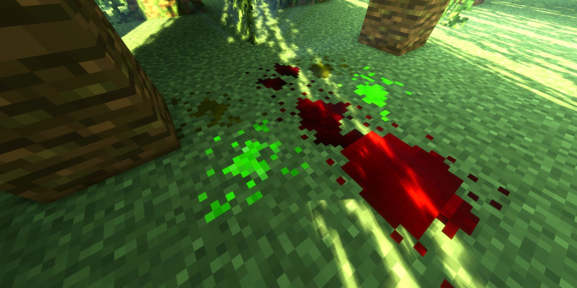 Multiple, messy pools of blood and bright green liquids on a grassy, forest floor.