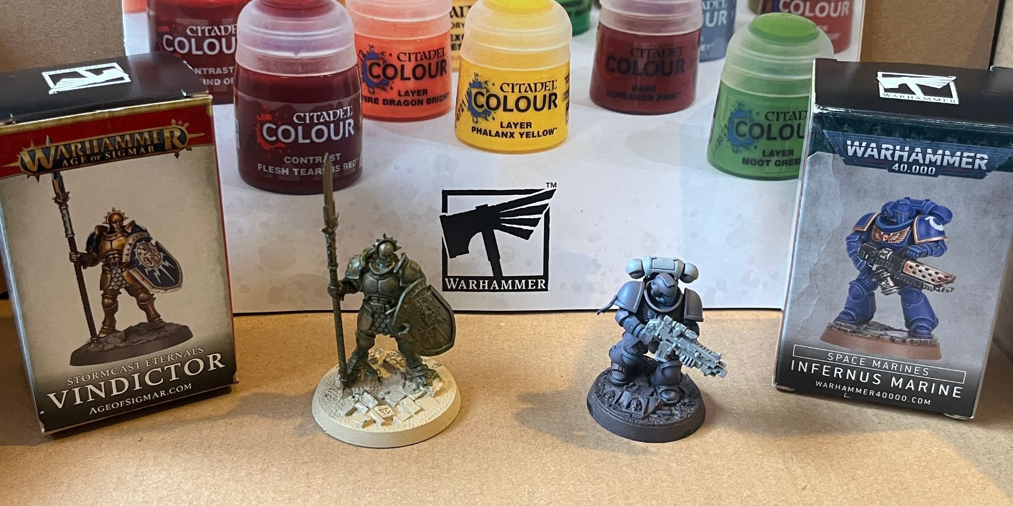 Warhammer painted space marine and vindictor miniatures in a box next to a small box with their names on