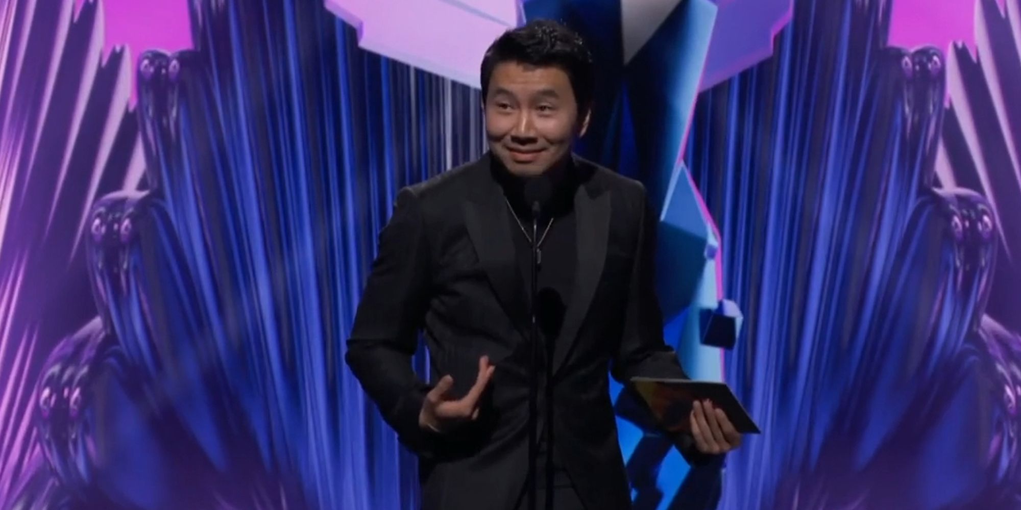actor Simu Liu standing in front of a mic at The Game Awards