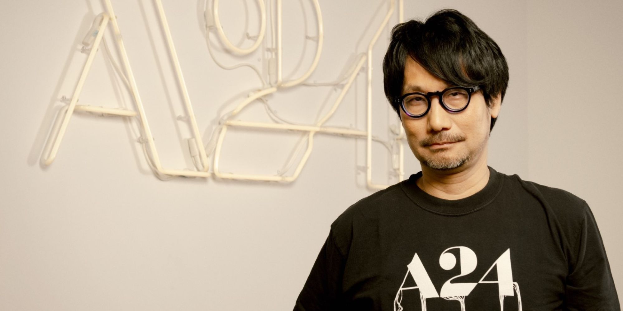 Hideo Kojima in front of the A24 logo, in an A24 shirt
