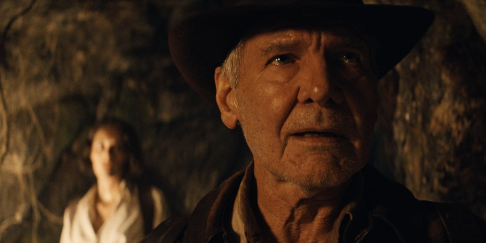 Indiana Jones looking straight ahead with an expression of relief as Helena is blurred out behind him in the distance.