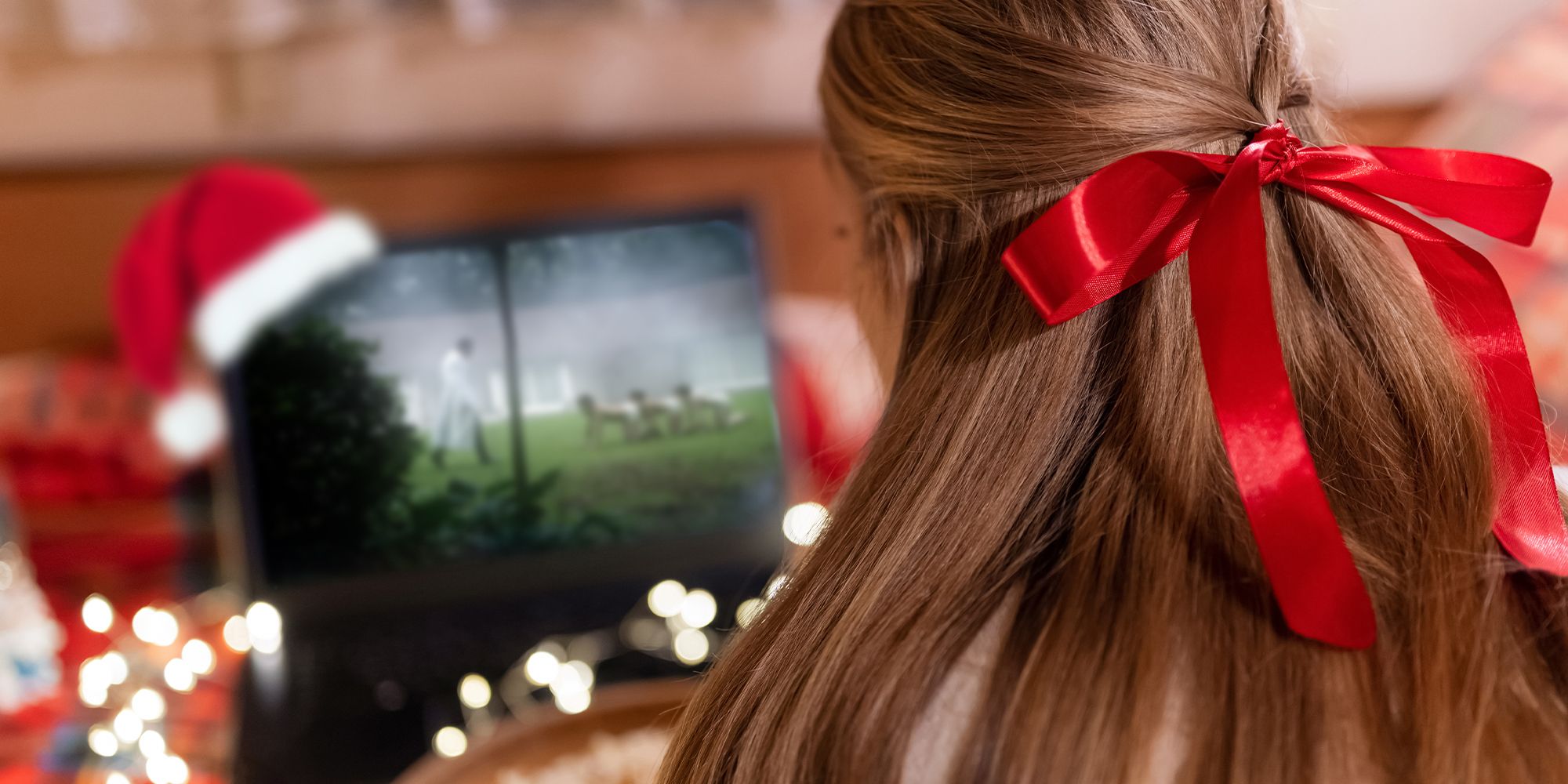 A girl with a red bow in her hair watching Human Centipede at Christmas
