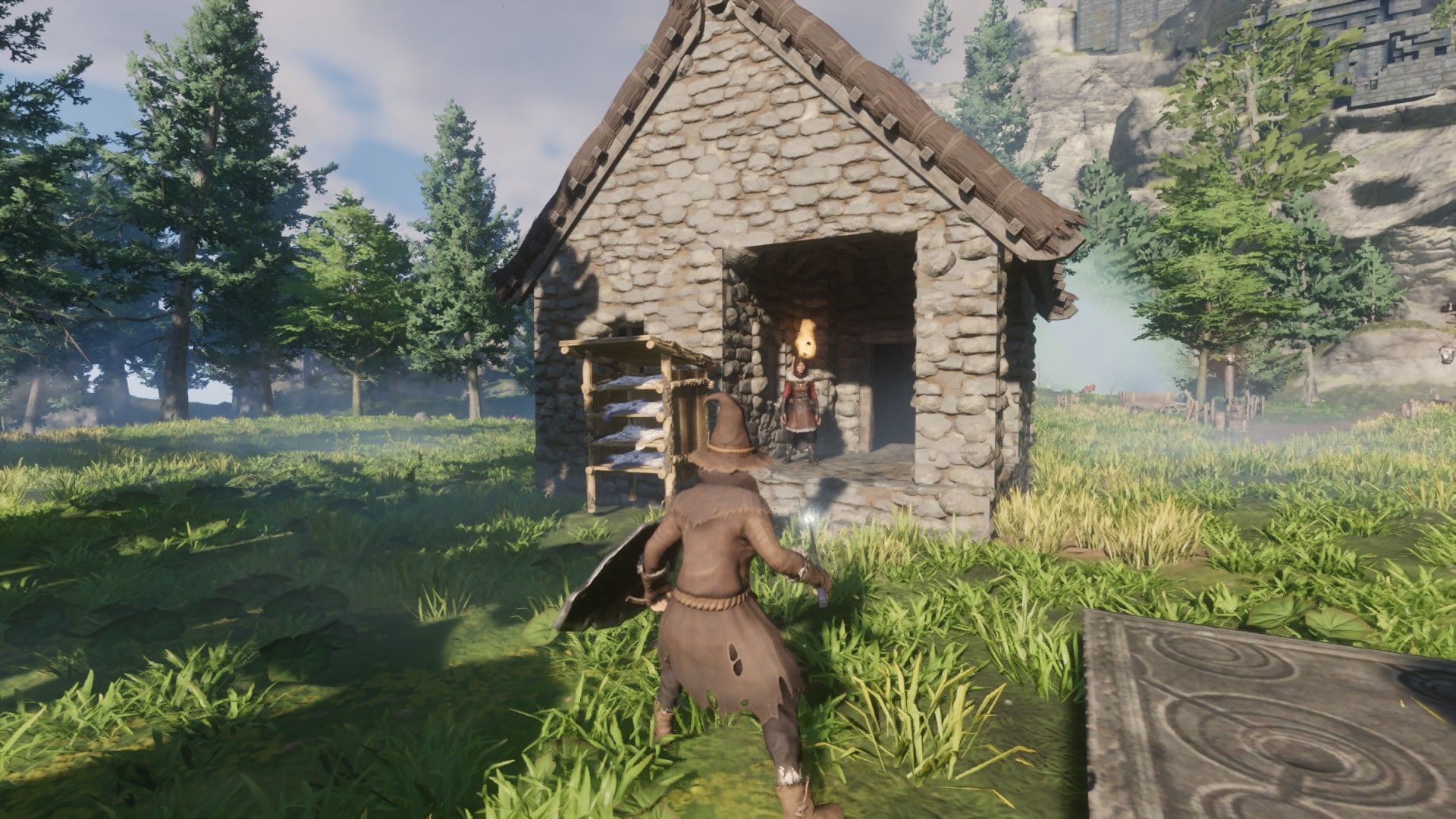 Eingehüllter Spieler mit Blick auf ein kleines Steinhaus